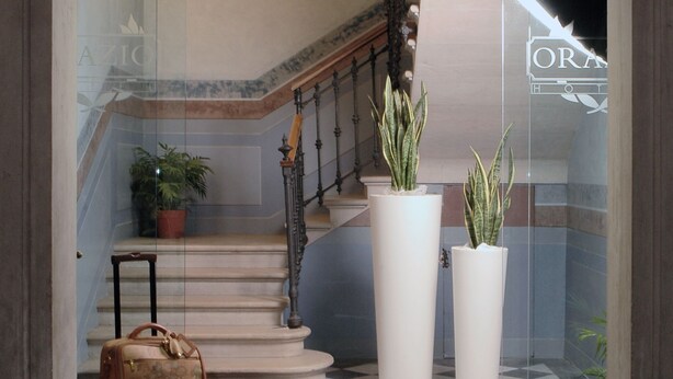 Un vestíbulo con piso a cuadros, una escalera y plantas en macetas.