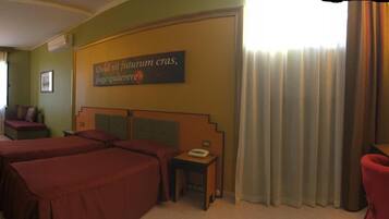 A hotel room with two beds, a desk, a chair, a nightstand, a telephone, and a window with curtains.