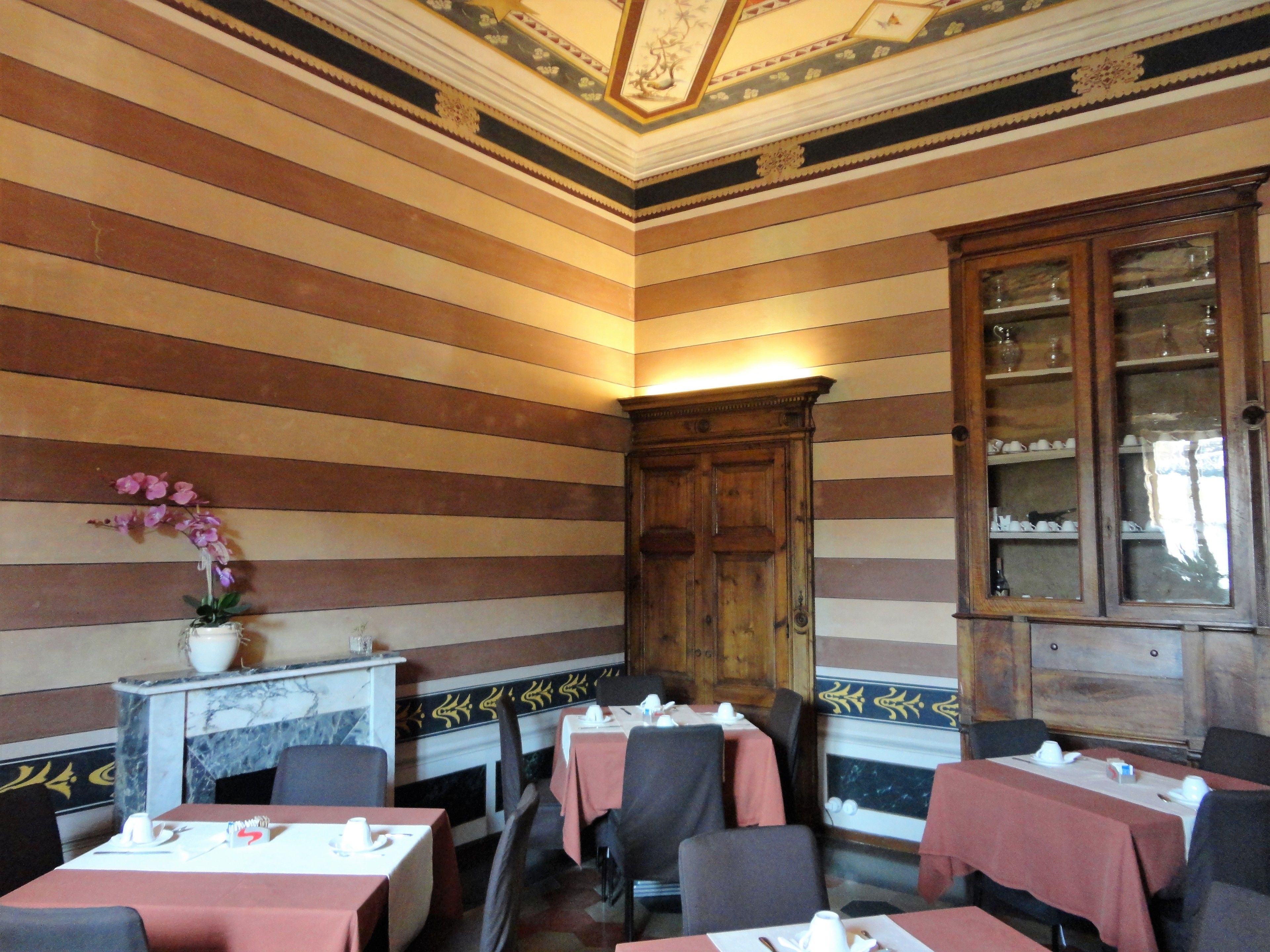 A dining area with striped walls, wooden cabinets, and tables set for dining.