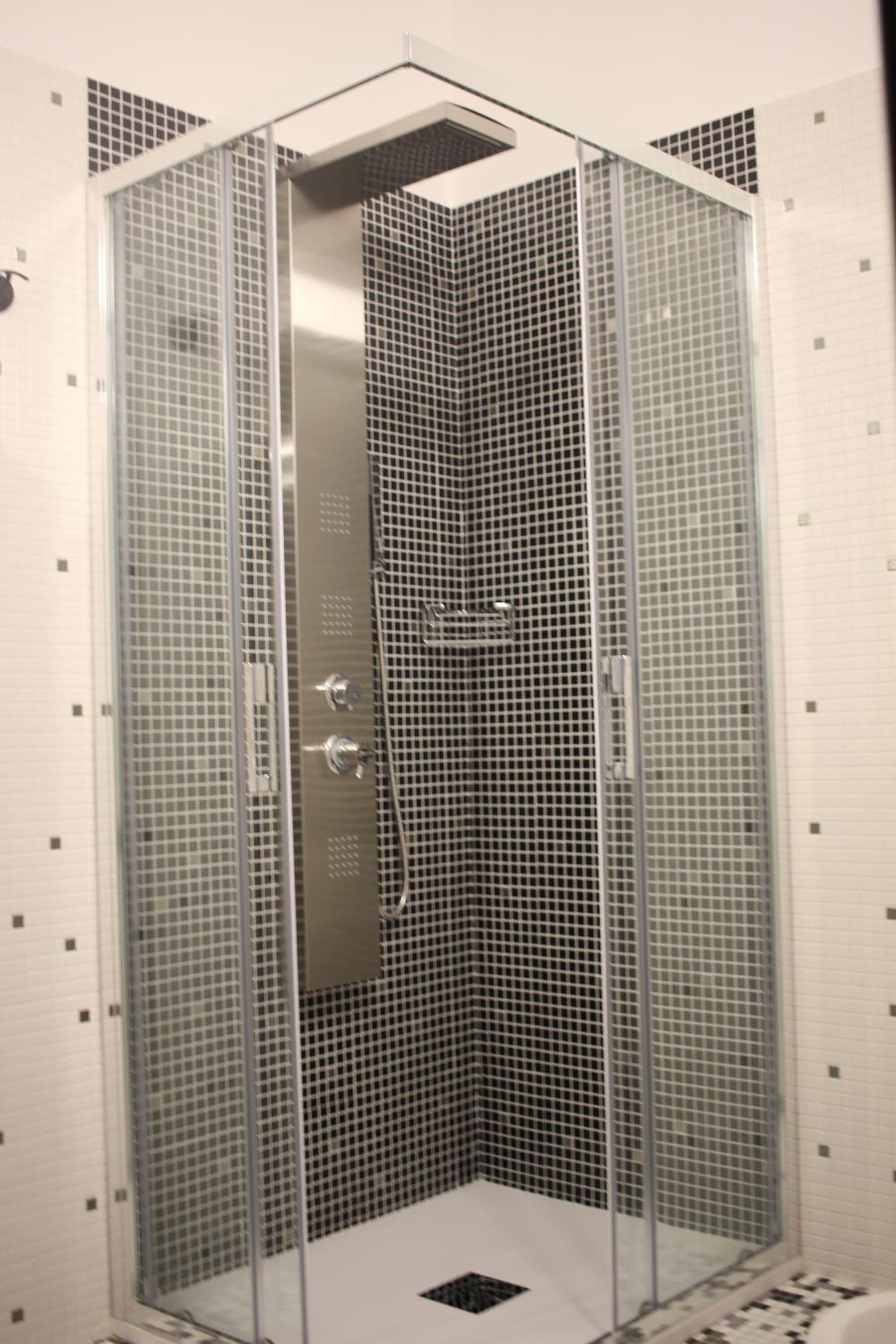 A walk-in shower with a glass door, tiled walls, and a metal showerhead.
