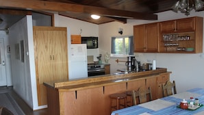 Een keuken met houten kastjes, een centraal eiland en een eethoek met een tafel.