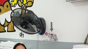 Un taulell de recepció amb superfície de vidre, un ventilador i un armari de primers auxilis a la paret.