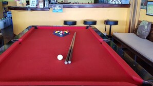 Taula de bitlles amb superfície vermella de feltre, una bola blanca i pilotes de bitlles.