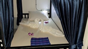 Un llit individual amb matalàssera blanca, llençol blau rayat i una disposició de tovalloles amb forma de cigne.