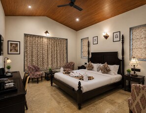 A hotel room with a large bed, two armchairs, a desk with a lamp, and a ceiling fan. - Park Exotica Resort & Spa - Near Fateh Sagar Lake, Udaipur (Udaipur)