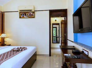 A hotel room with a bed, a desk, a television, and a painting on the wall. - Park Exotica Resort & Spa - Near Fateh Sagar Lake, Udaipur (Udaipur)