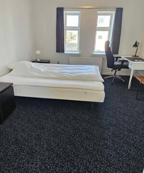 A hotel room with a bed, a desk, a chair, and two windows. - Bed and Breakfast Phønix (Holstebro)