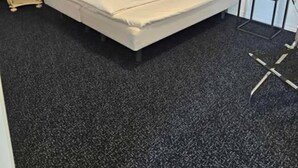 Ein Schlafzimmer mit einem großen Bett, einem kleinen Tisch, einem Stuhl und einer Lampe.
