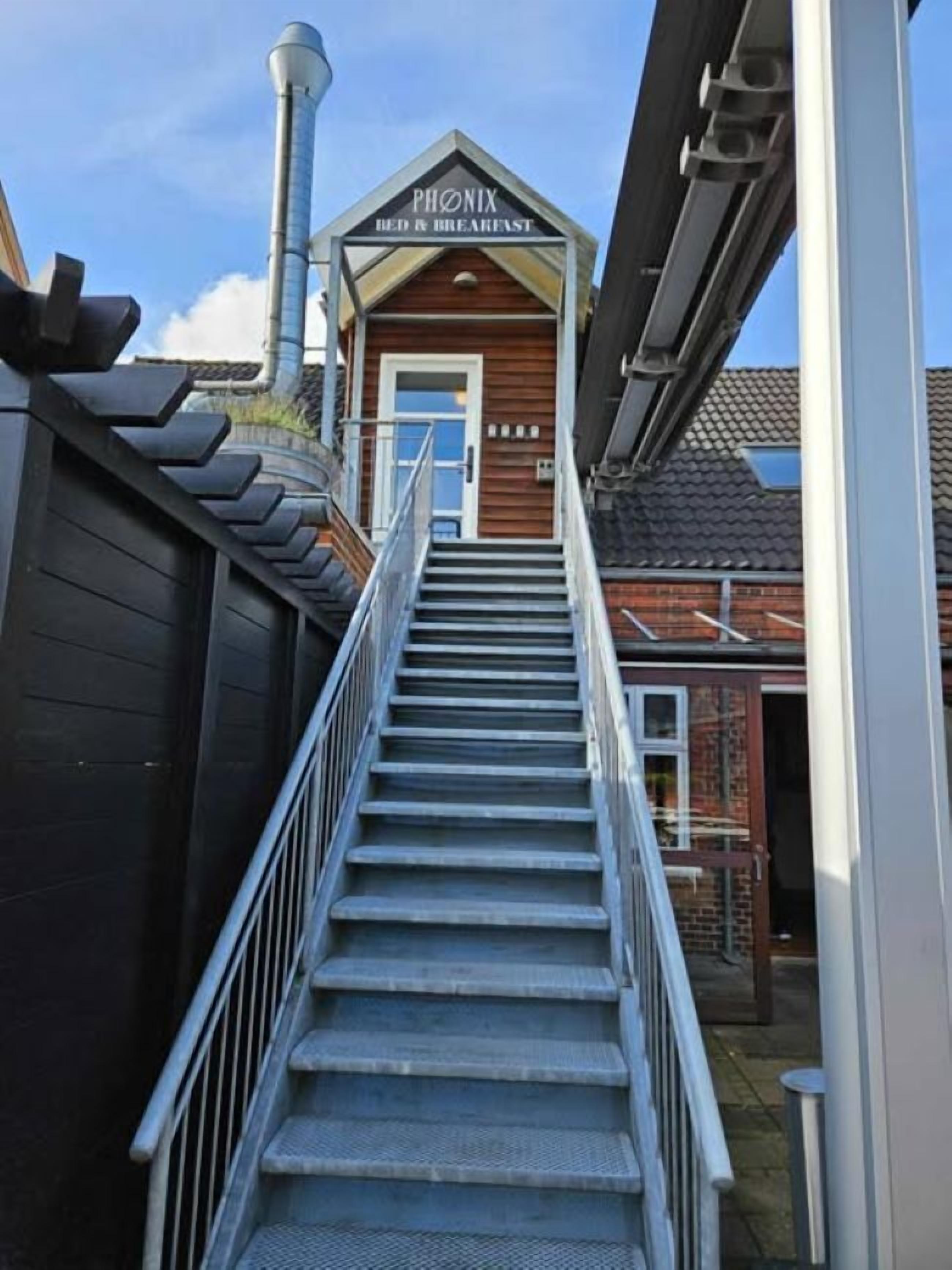 A staircase leading to a bed and breakfast named 'PHONIX' with a wooden exterior and a metal railing.