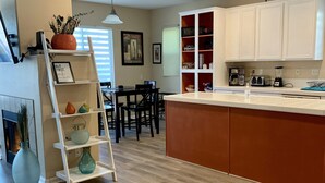 A modern kitchen with white cabinets, a wooden floor, and a central island.