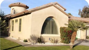 A single-story house with a curved roof, a large arched window, and a small porch area.