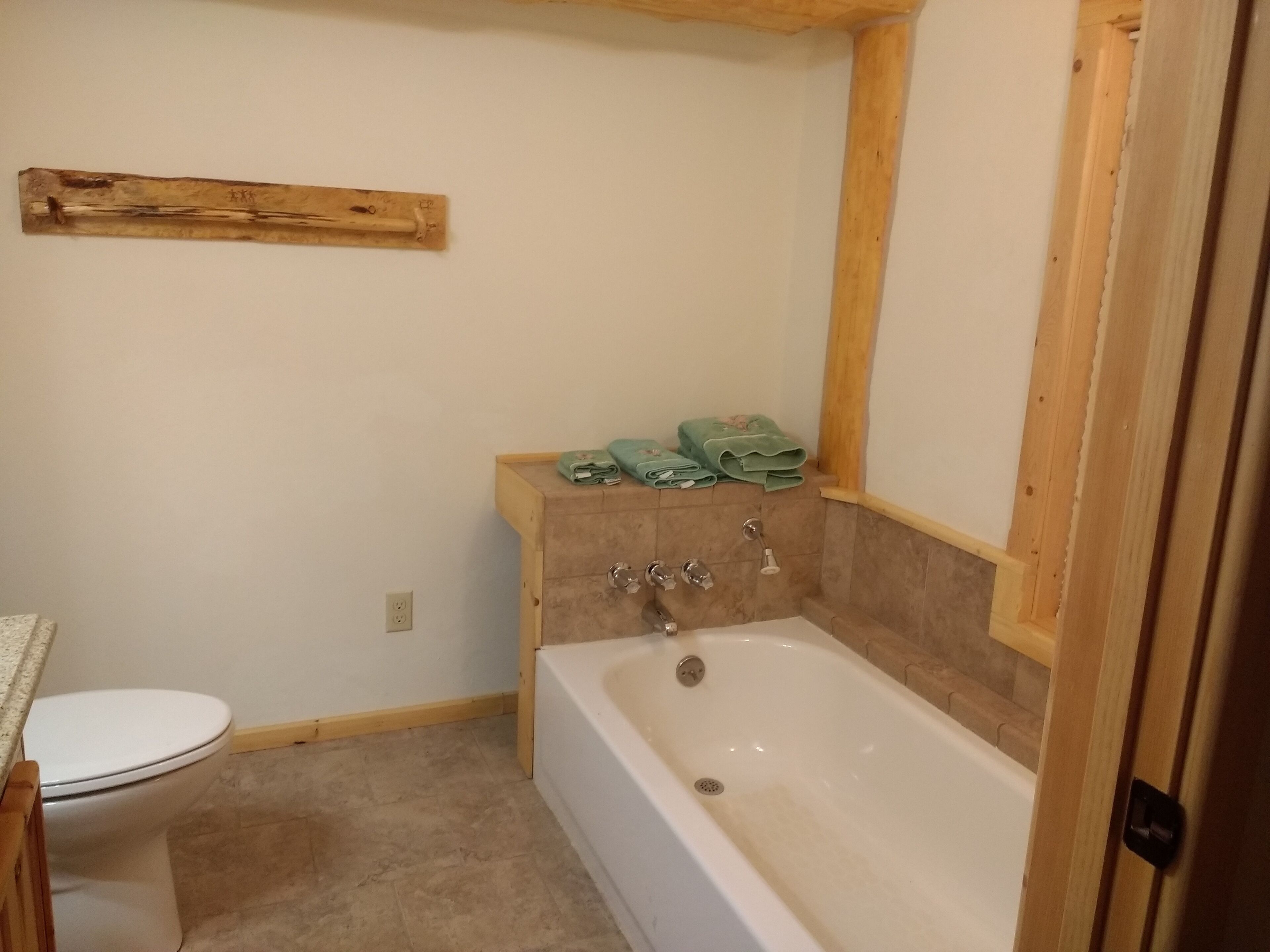 Ein Badezimmer mit Badewanne, Toilette und einem Holzboden mit Handtüchern.