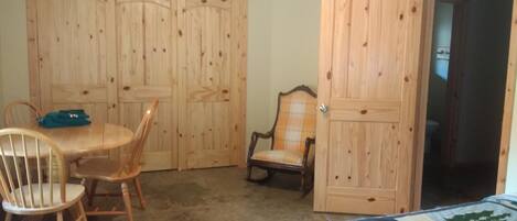 Ein Zimmer mit Holztisch und -stühlen, einer Bettdecke und Holzschränken.