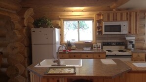 A log cabin kitchen with a refrigerator, sink, stove, and microwave. - Log cabin for salmon, fishing, hiking, cross-country skiing, 50 minutes to ski (Pollock)