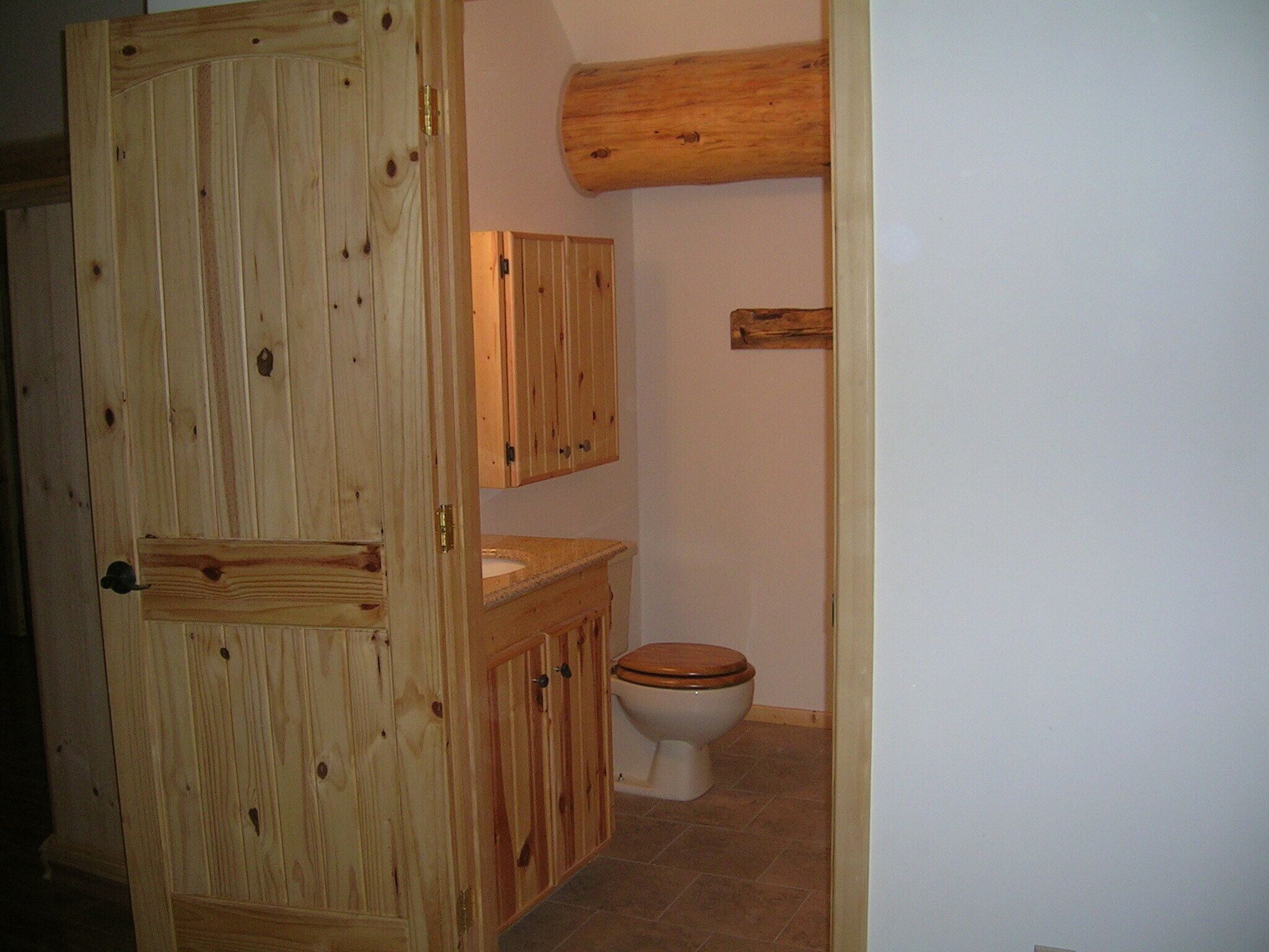 Ein Badezimmer aus Holz mit Toilette, Waschbecken und Schrank.