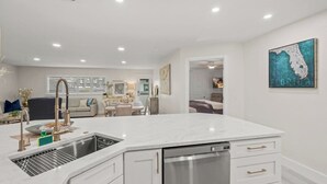 Una cocina moderna con encimera de mármol blanco, electrodomésticos de acero inoxidable y lavavajillas integrado.