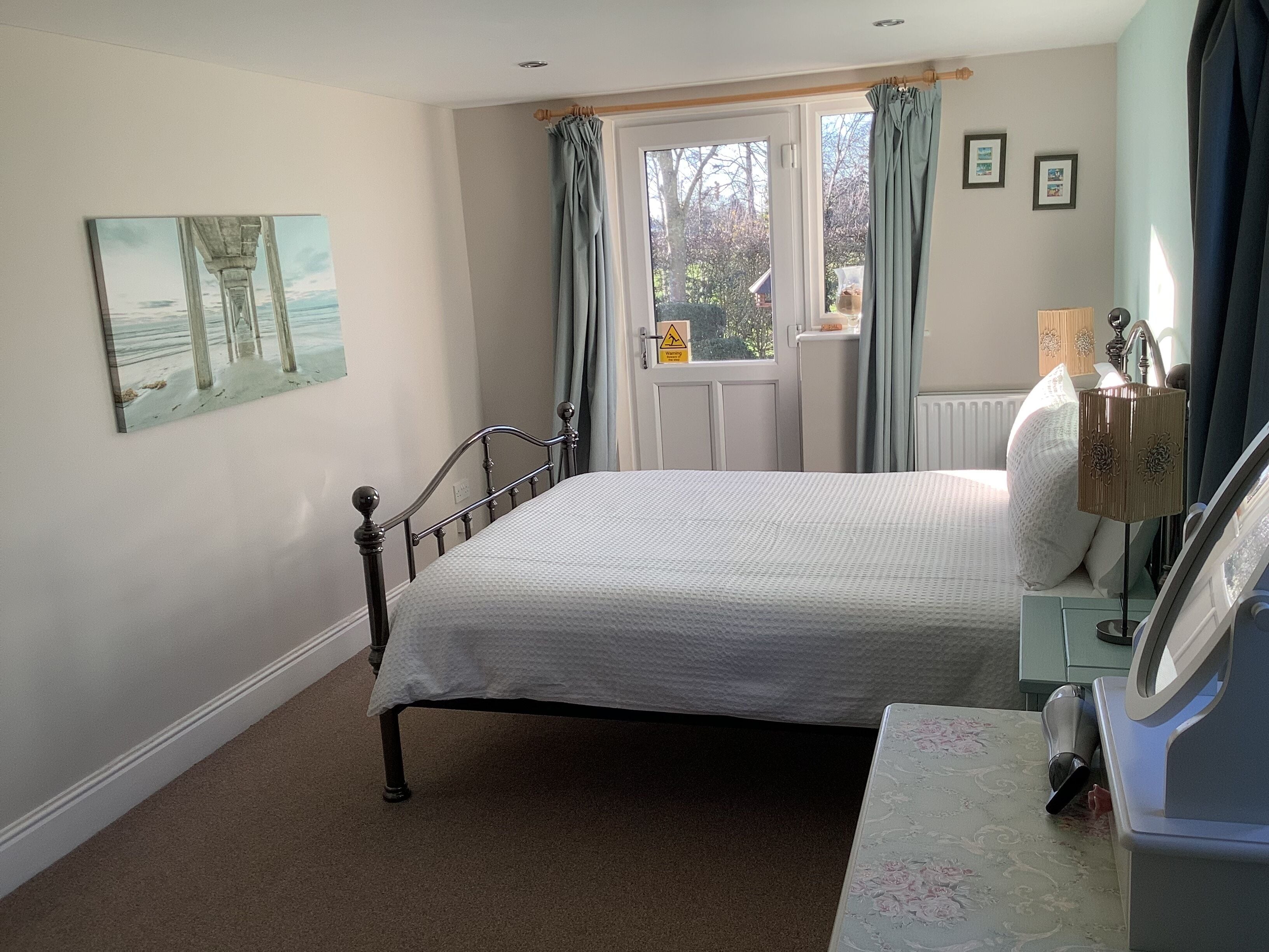 A bedroom with a bed, a dresser, a lamp, and a window with curtains.