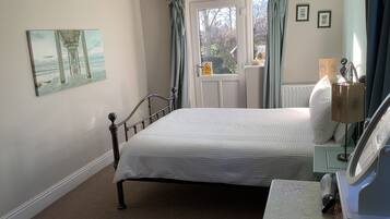 A bedroom with a bed, a dresser, a lamp, and a window with curtains.