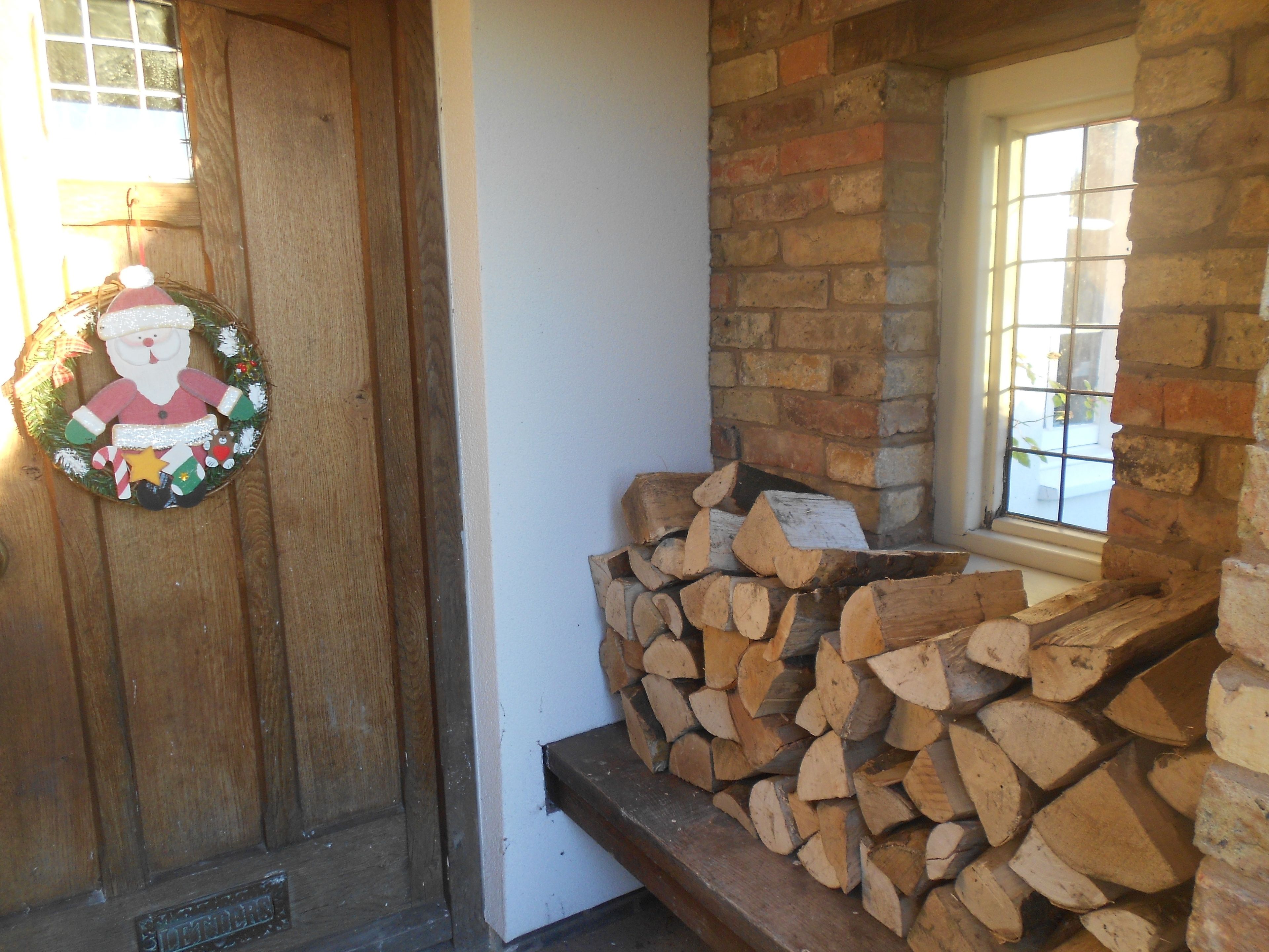 A wooden door with a Christmas wreath, a brick wall, and a window.