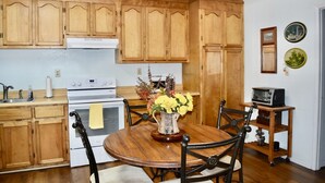 Une cuisine avec des meubles de rangement en bois, une cuisinière, un évier et une table à manger avec des chaises.