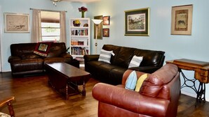 Un salon avec un canapé en cuir marron, une table basse en bois et une bibliothèque remplie de livres.