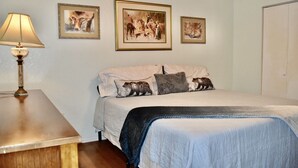 Une chambre à coucher avec un lit, des oreillers, une lampe et trois tableaux encadrés accrochés au mur.