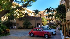 Ein Hotelinnenhof mit einem roten Oldtimer im Zentrum, umgeben von Palmen und einem Poolbereich.