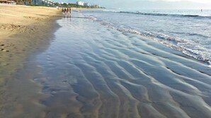 Ein Strand mit wellenartigen Sandmustern und freiem Blick auf den Ozean.