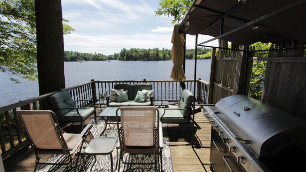 Une terrasse dotée de mobilier d’extérieur, d’un barbecue et offrant une vue sur un lac.