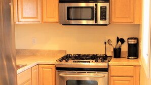 Une cuisine dotée de meubles en bois, d’un réfrigérateur en acier inoxydable, d’un four à micro-ondes, d’une cuisinière et d’un four traditionnel.