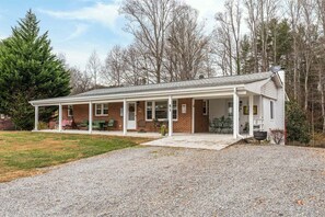 A single-story building with a covered porch, a gravel driveway, and a brick exterior.
