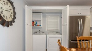 A compact kitchen with a clock, a refrigerator, a stove, and a washing machine. - Spacious 4BR getaway in downtown Brevard, perfect for family adventures! (Brevard)