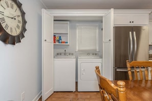 Een kleine keuken met een klok, een koelkast, een fornuis en een wasmachine.