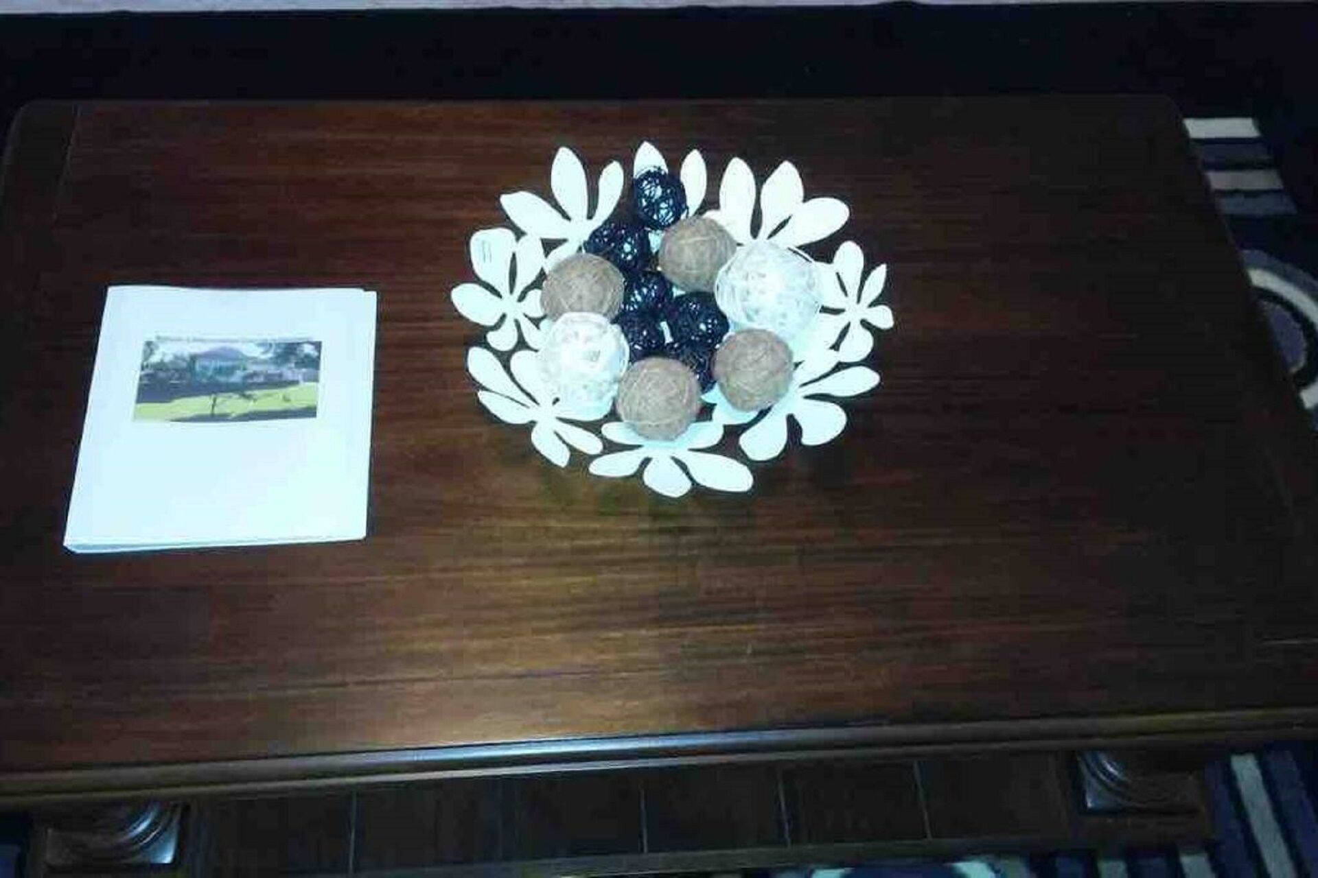 A wooden table with a decorative plate of spherical objects and a photograph.
