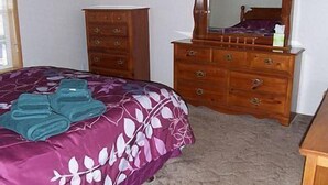 Een slaapkamer met een bed, een dressoir en een spiegel.