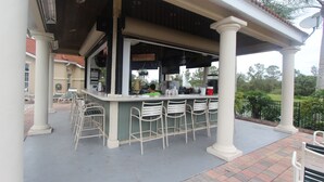 Een terras met een bar en verschillende stoelen.