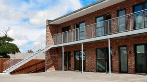 A modern building with a brick facade, a balcony with metal railings, and a staircase leading to the entrance. - Hotel Phønix (Holstebro)