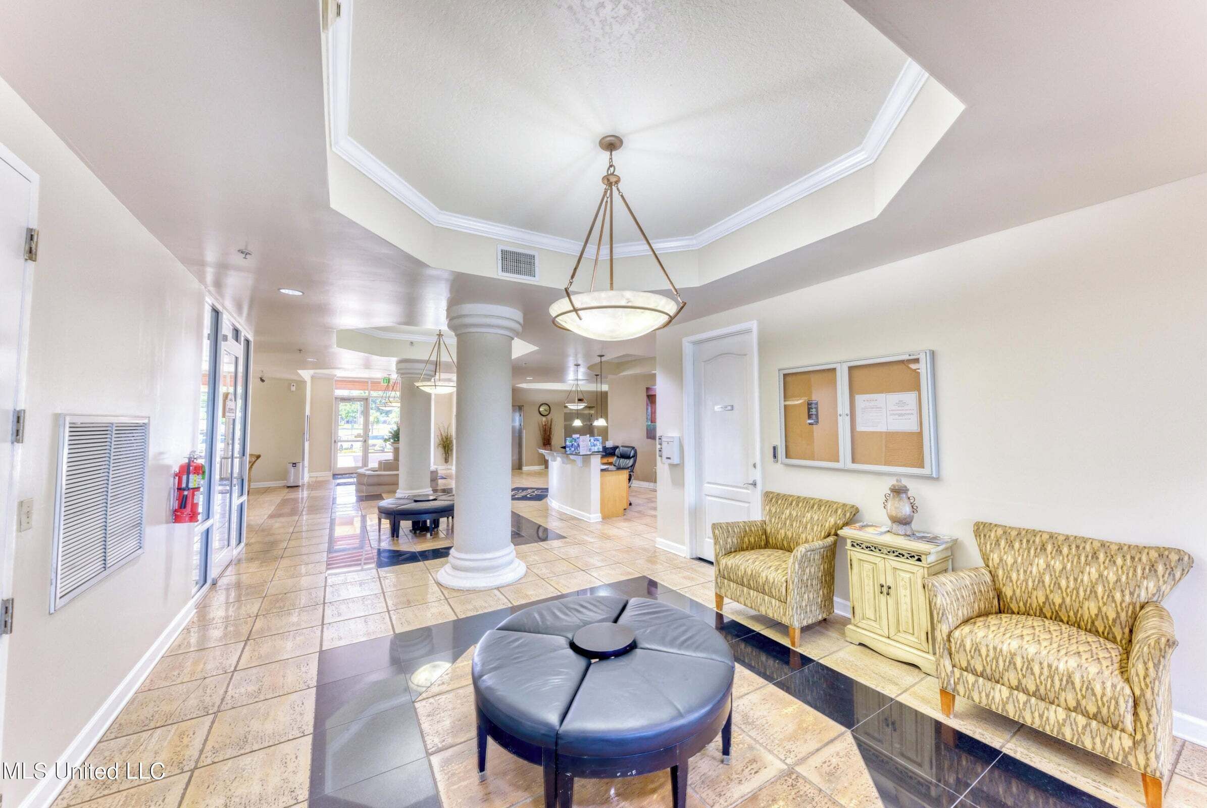 A spacious lobby with a high ceiling, a central seating area, and a reception desk.