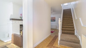 Un escalier avec des marches recouvertes de moquette et des rampes blanches, menant à l’étage supérieur.
