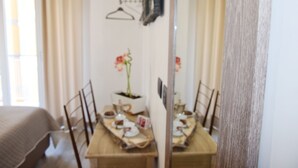 Un comedor con una mesa preparada para dos personas, una planta en maceta y un espejo que refleja la habitación.