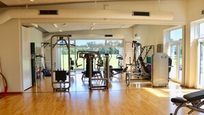 A gym with exercise equipment, large windows, and a wooden floor. - Plexus Hytterne (Holstebro)