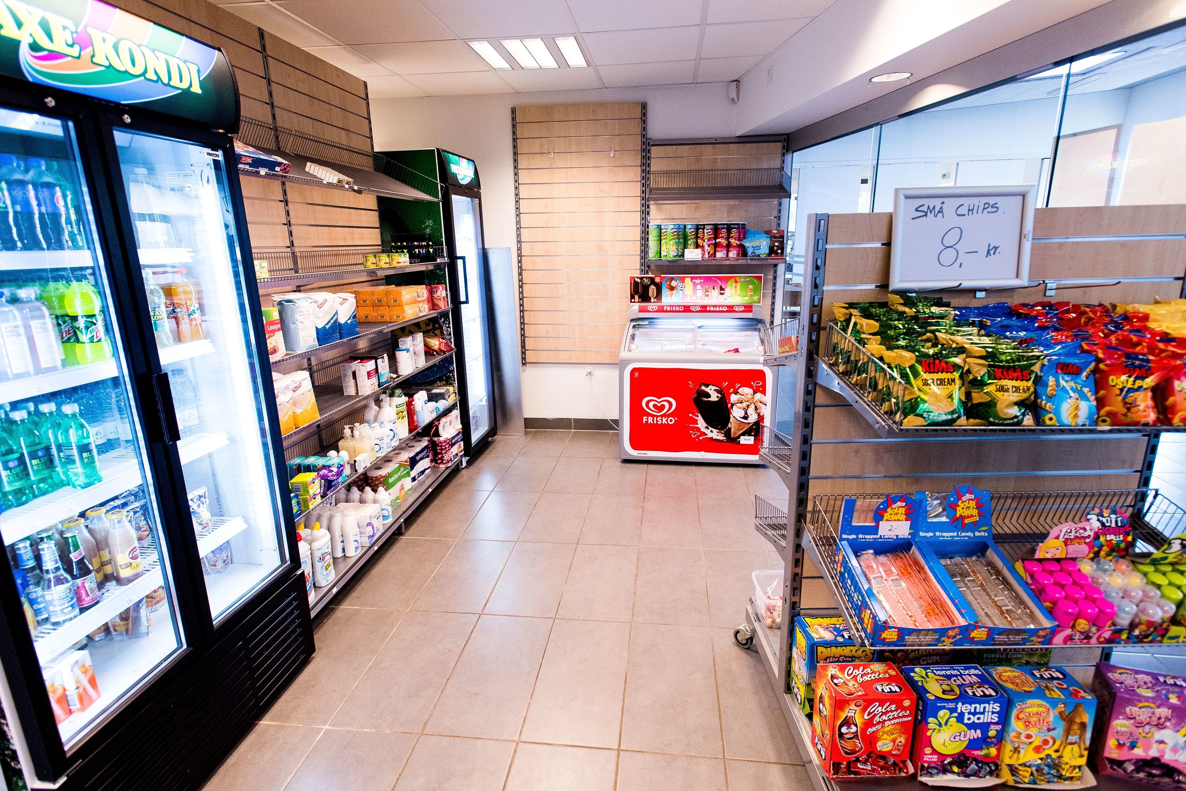 Passís d'un supermercat amb begudes refrigerades, aperitius i una secció congelada.