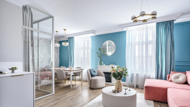 A modern living room with a dining area, a large mirror, and a pink sofa.