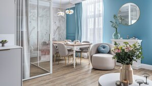 A modern living room with a dining area, a glass partition, and a large mirror.