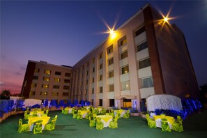 A hotel courtyard at dusk with tables and chairs arranged for an event. - The Piccadily Lucknow (Lucknow)
