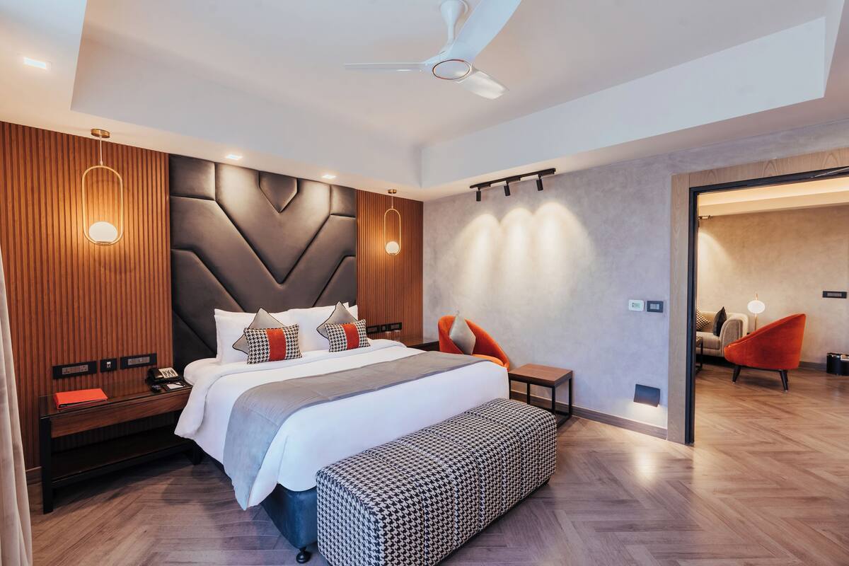 Quarto de hotel moderno com uma cama grande, uma escrivaninha, um banco e um ventilador de teto.