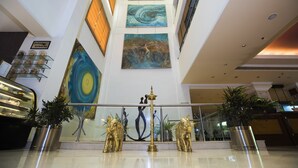A lobby with a high ceiling, artwork on the walls, a reception desk, and a decorative lamp. - The Piccadily Lucknow (Lucknow)