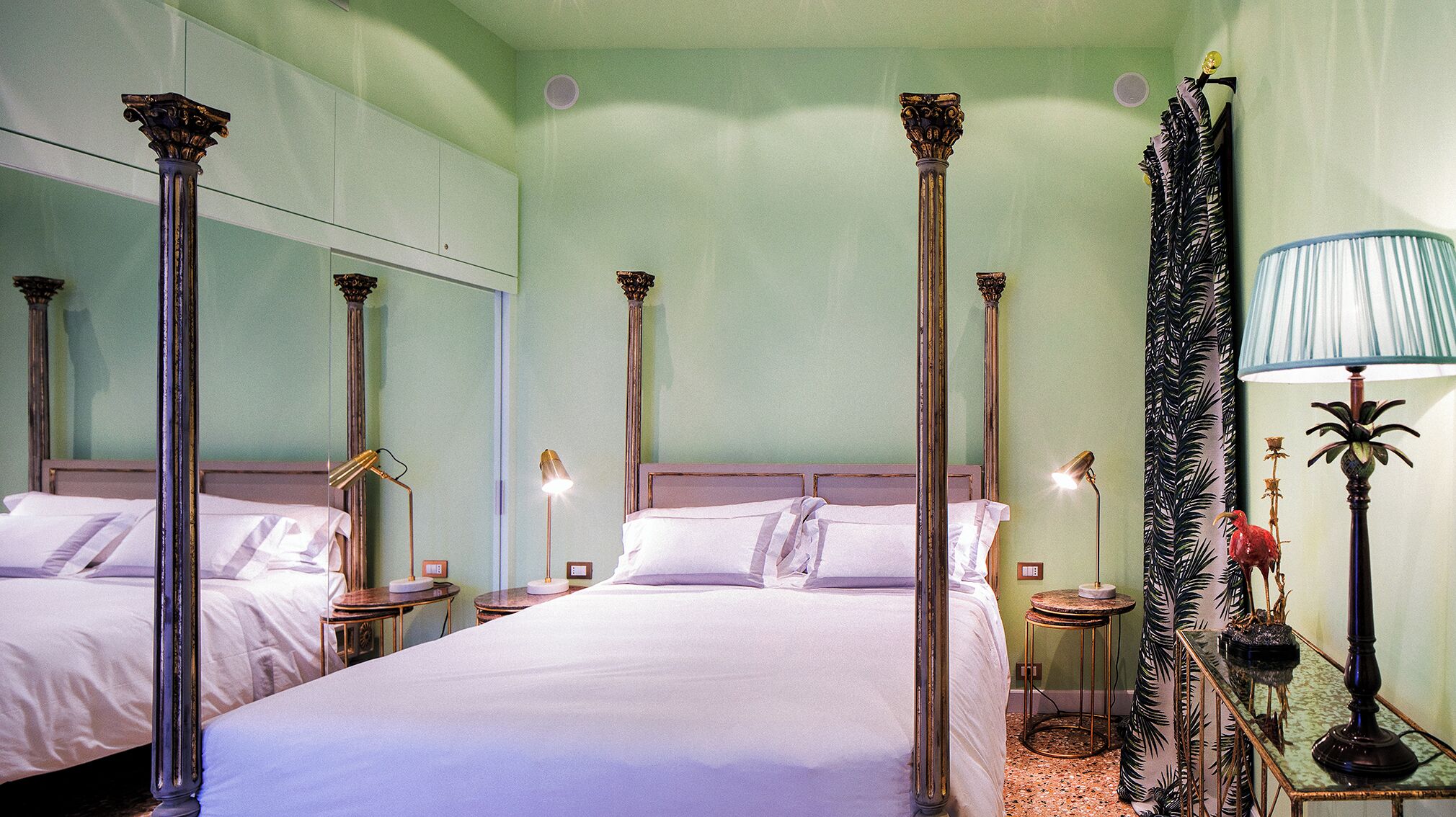 Una habitación de hotel con cuatro camas, cada una con una mesita de noche y una lámpara.