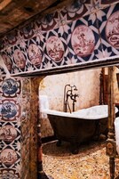 Un bagno con una vasca da bagno vintage, pareti in maioliche decorate e un pavimento in marmo.