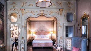 A luxurious bedroom with an ornate bed, a chandelier, a statue, and a large mirror. - Hotel Heureka  (Venice)